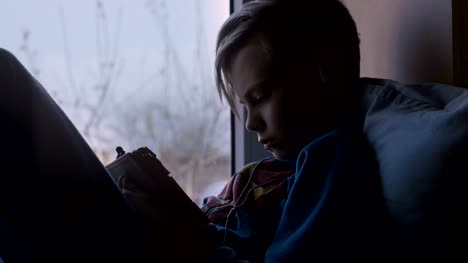 Kind-mit-Tablet-auf-Fensterbank
