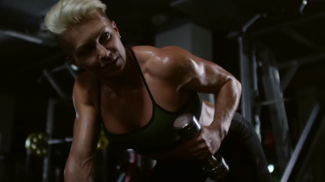 Muscular-culturista-femenina-haciendo-Bent-en-la-pesa-de-gimnasia-rizos