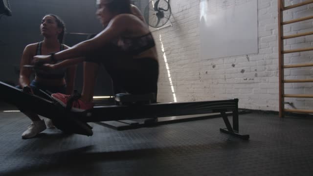Woman-exercising-on-row-machine-with-trainers