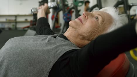 Ältere-Frau-mit-Hanteln-im-Fitnessstudio-trainieren