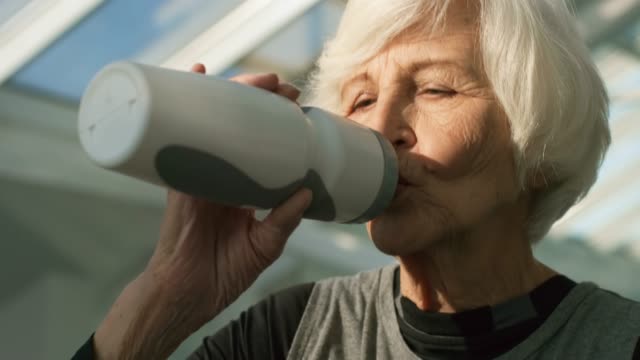 Ältere-Frau-Trinkwasser-während-des-Trainings