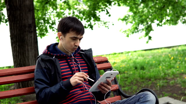El-hombre-está-utilizando-una-tableta-en-el-parque.
