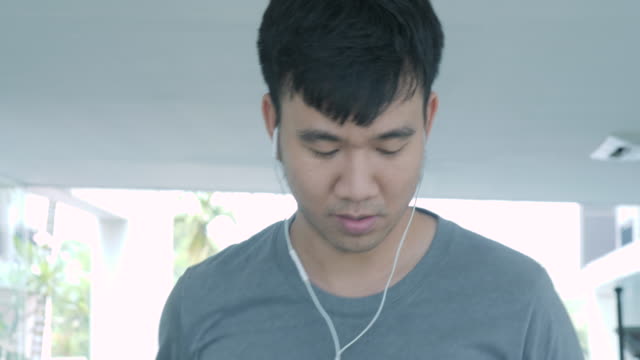Joven-asiática-corriendo-en-la-caminadora-en-el-gimnasio-con-auriculares