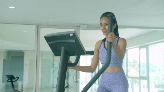 Chica-haciendo-ejercicio-de-cardio-en-la-máquina-elíptica-en-el-gimnasio