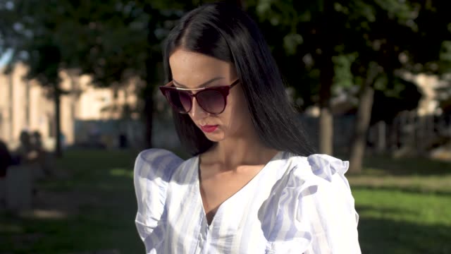 Schöne-junge-Frau-in-Sonnenbrille-Eingabe-auf-ihrem-Laptop-im-park