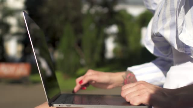 Mujer-de-negocios-trabajando-en-ordenador-portátil-sentado-en-un-banco-de-Parque