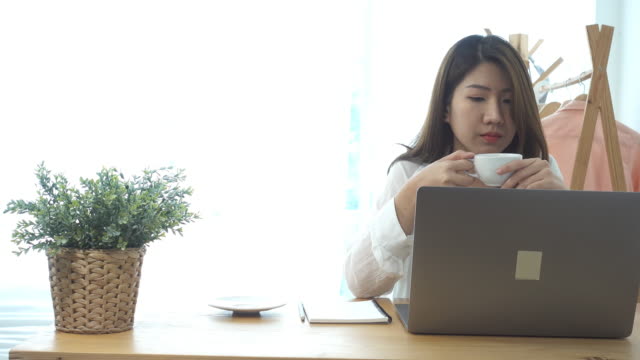 Bella-mujer-sonriente-joven-trabajando-en-ordenador-portátil-mientras-disfruta-de-beber-café-caliente-sentado-en-una-sala-de-estar-en-casa.-Disfrutando-en-casa.-Mujer-de-negocios-asiáticos-trabajando-en-su-oficina-en-casa.