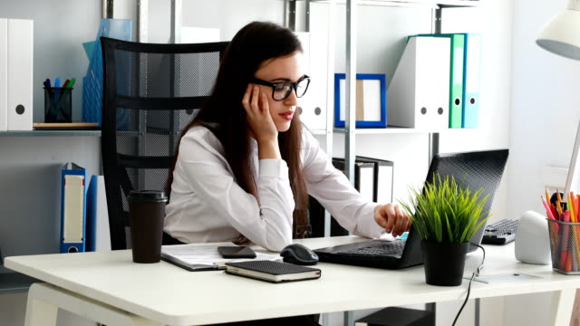 Frau-stützen-Kopf-in-der-hand-und-mit-Laptop-im-modernen-Büro