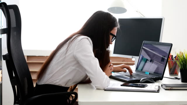 businesswoman-setting-aside-cup-and-puting-head-on-laptop