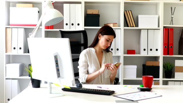 businesswoman-sitting-in-office-chair-and-using-smartphone
