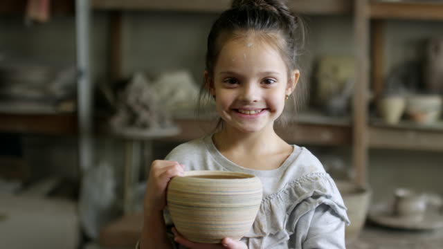 Niedliche-kleine-Mädchen-posiert-mit-Keramiktopf