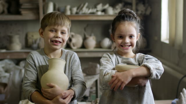 Glückliche-kleine-Kinder-posiert-in-der-Keramikwerkstatt