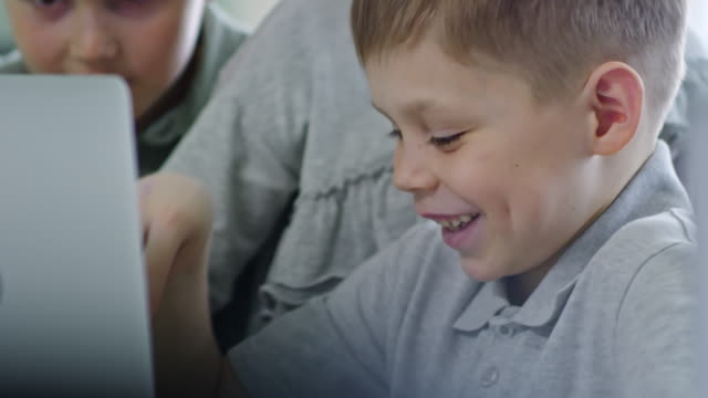 Junge-Lächeln-wenn-mittels-Laptop-mit-Klassenkameraden