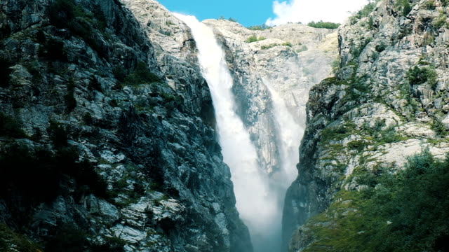 Huge-waterfall-in-the-mountains,-a-powerful-stream-of-water-falls-from-the-cliff,-slow-motion