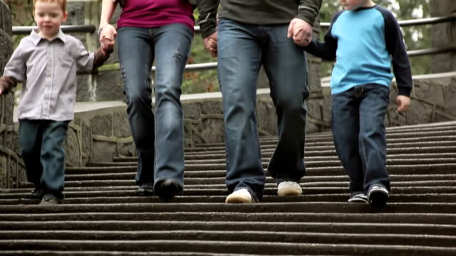 Mutter-und-Vater-halten-ihrer-Söhne-Hände,-wie-sie-einige-Park-Treppe-hinunter-gehen