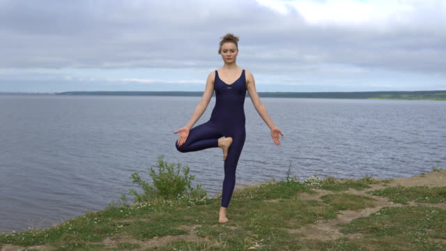Yoga-woman-in-sportswear-pose-against-lake