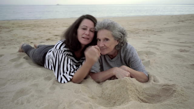 Mujeres-adultas-felices-divirtiéndose-mientras-está-acostado-en-la-playa-de-arena