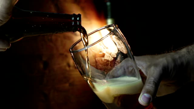 Mann-gießt-frisches-Bier-mit-Schaum-ins-Getränk-Pint-Glas-mit-Eis-gefrorenen-Tropfen-auf-gold-braune-Hintergrund,-Spaß-und-Ernährung-essen