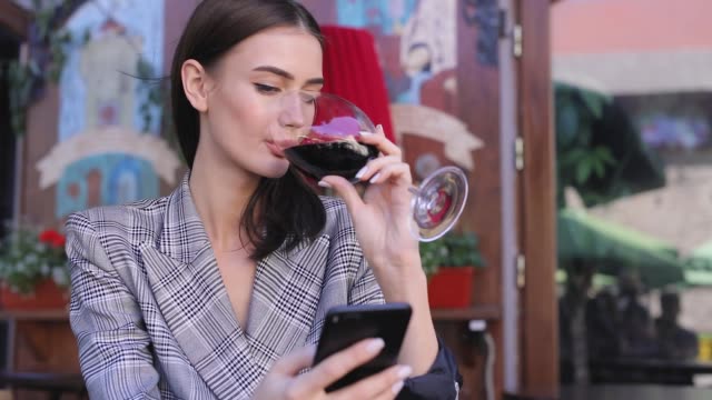 Lächelnde-Frau-trinken-Wein-und-mit-Telefon-im-Restaurant