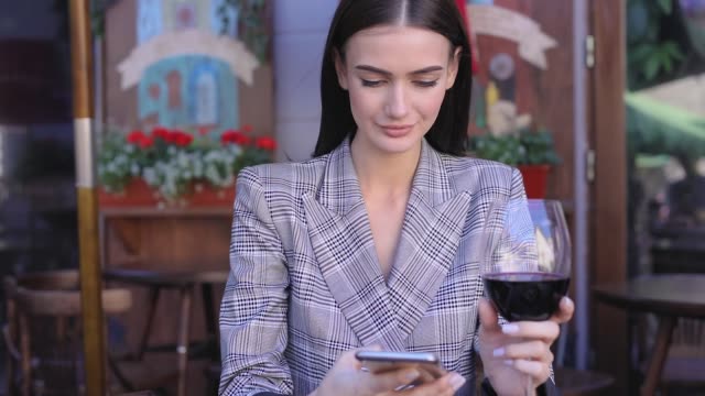 Lächelnde-Frau-trinken-Wein-und-mit-Telefon-im-Restaurant