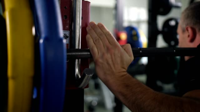 Close-up.-Hands-of-the-bodybuilder-who-puts-the-barbell-on-the-hook-4K-Slow-Mo