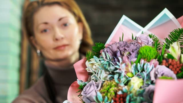 Frau-Blumengeschäft-mit-einen-schönen-Blumenstrauß.-Das-Bouquet-im-Vordergrund-mit-einem-unscharfen-Hintergrund.