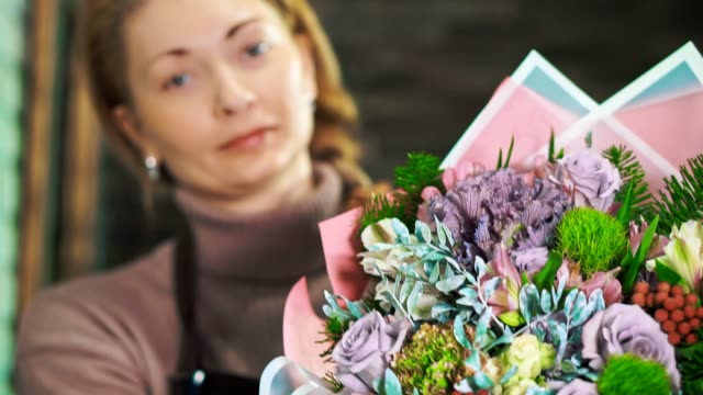 Frau-Blumengeschäft-mit-einen-schönen-Blumenstrauß.-Das-Bouquet-im-Vordergrund-mit-einem-unscharfen-Hintergrund.