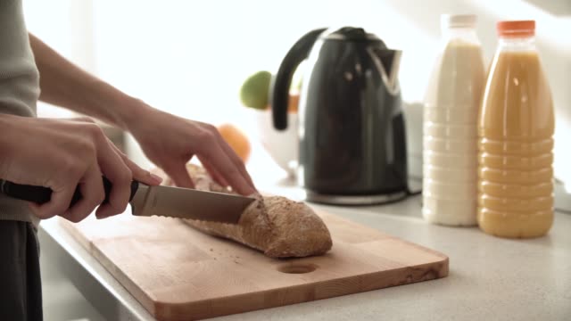 Cutting-Bread-On-Wooden-Board-By-Woman-Hands-Closeup