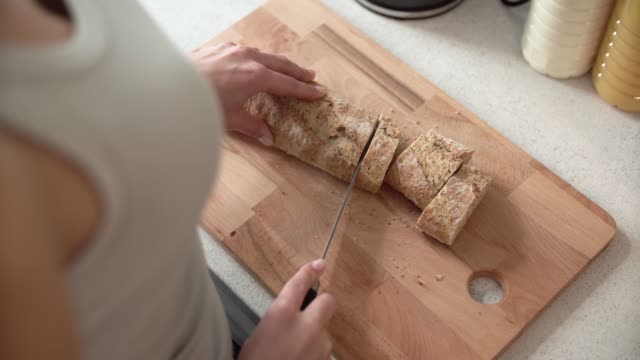 Cutting-Bread-On-Wooden-Board-By-Woman-Hands-Closeup