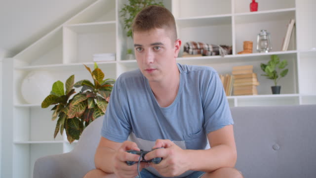 Closeup-portrait-of-adult-attractive-caucasian-man-playing-video-games-sitting-on-couch-indoors