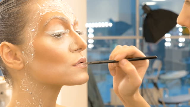 Der-Make-up-Künstler-malt-das-Modell-Lippen-mit-einer-speziellen-Bürste.-Close-up