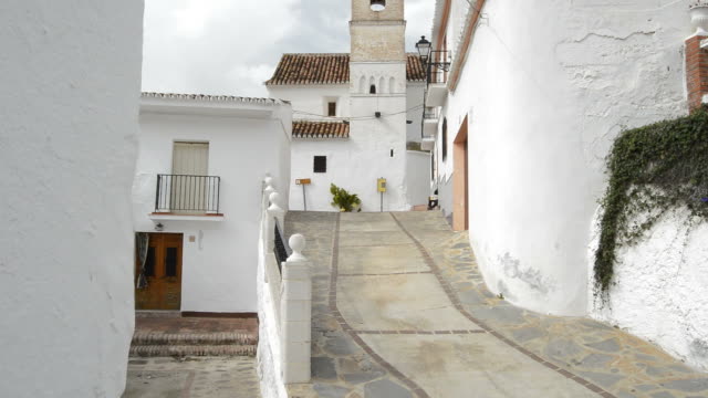 Street-in-the-andalusian-village-of-Daimalos-with-a-old-christian-church,-tilt