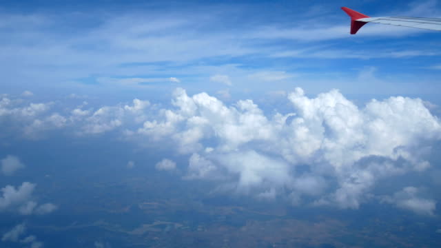 Imágenes-de-4K.-viajando-por-el-aire.-vista-aérea-a-través-de-una-ventana-del-avión.-avión-de-ala-y-hermosas-nubes-blancas-en-el-cielo-azul-de-fondo