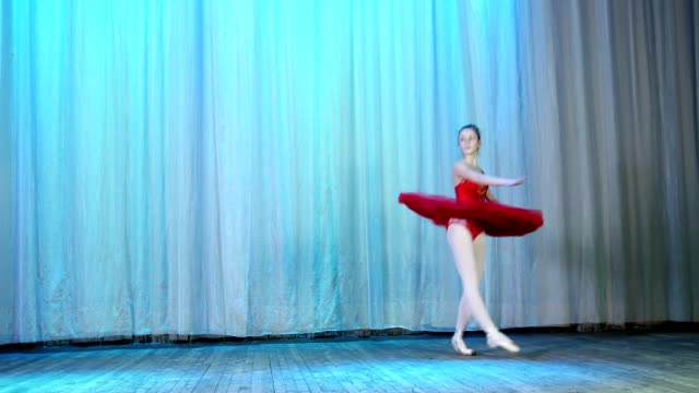 ballet-rehearsal,-on-the-stage-of-the-old-theater-hall.-Young-ballerina-in-red-ballet-tutu-and-pointe-shoes,-dances-elegantly-certain-ballet-motion,-tour-en-dedane