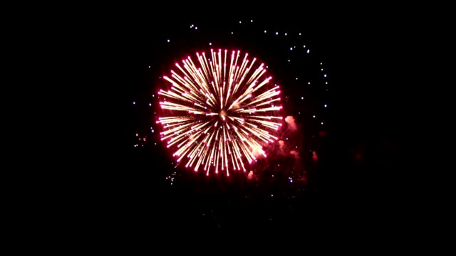 Bright-fireworks-on-the-holiday.-In-the-night-sky-shines-a-bright-fireball-crimson.-An-interesting-ball-is-in-the-center-of-fireworks,-around-small-balls-of-different-colors