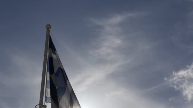 Bandera-de-Grecia-contra-el-sol-y-el-cielo-azul-de-inclinación-4K