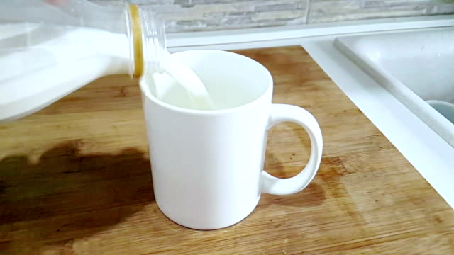 frische-weiße-Milch-Eingießen-in-Trinkglas-auf-Küche-Hintergrund,-schießen-mit-Slow-Motion,-Diät-und-gesunde-Ernährung-Frühstück