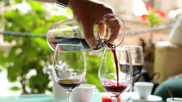 Man-gießt-Wein-Weingläser-im-Straßencafé