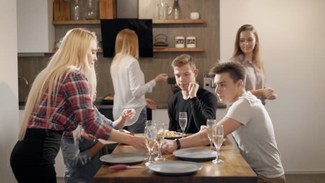 Young-people-sitting-at-table-with-food-and-drinks