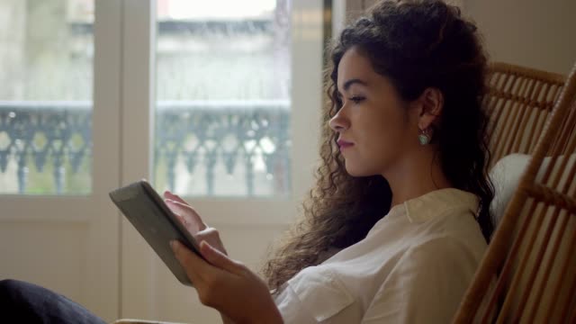 Attractive-girl-with-curly-hair-using-tablet-pc-at-home