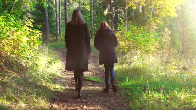 Frau-und-ihre-Tochter-gehen-im-Herbstwald.