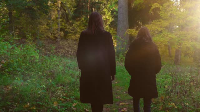Mujer-y-su-hija-camina-en-el-bosque-de-otoño.