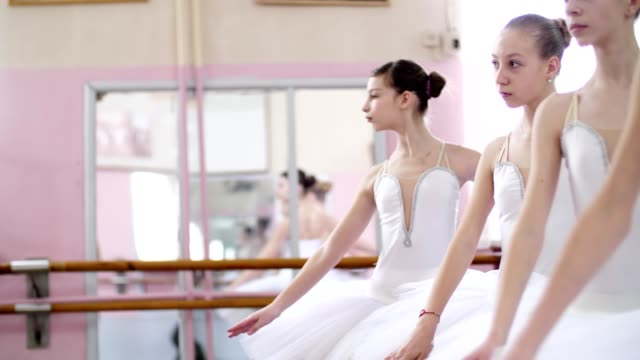 in-ballet-hall,-Young-ballerinas-perform-allonge,-moving-hands-elegantly-up-and-down,-close-up