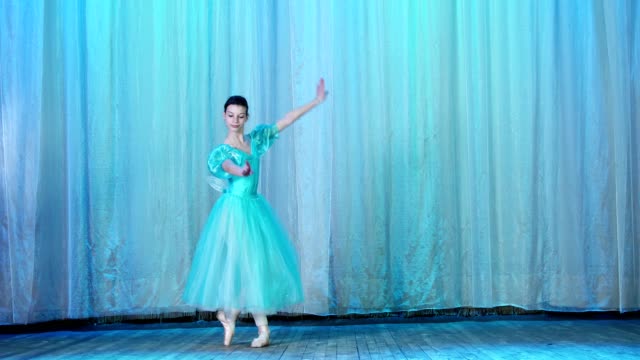 Ballett-Probe-auf-der-Bühne-des-alten-Theatersaal.-Jungen-Ballerina-in-blau-Ballett-Kleid-und-Pointe-Schuhe,-tanzt-elegant-bestimmte-Bewegung-Ballett-Arabesque