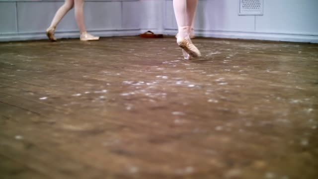 close-up,-in-ballet-class,-on-an-old-wooden-floor,-ballerina-performs-glissade-en-tournant,-She-moving-through-the-ballet-class-elegantly