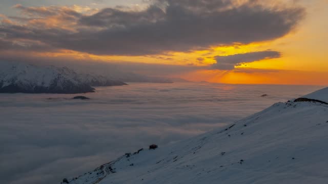 Zeitraffer-Sonnenuntergang-über-schneebedeckten-und-nebligen-Berge