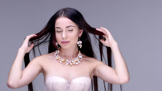 Beautiful-woman-posing-in-studio.-She-shows-women's-jewelry