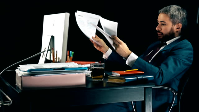 Frustrated-bearded-businessman-looks-through-business-papers-and-throws-them-away.-Black-background.-FullHD-video