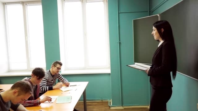 Woman-teacher-standing-in-front-of-students-during-a-lesson-in-classroom