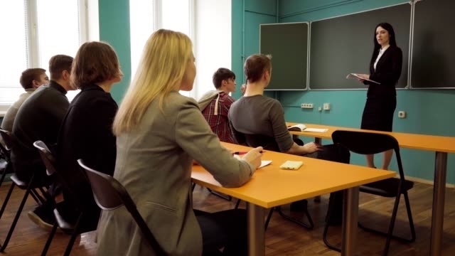 Woman-teacher-talking-to-students-during-a-lesson-in-classroom
